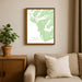 Framed map of Tofino on a wall above a beige sofa with a plant beside it.