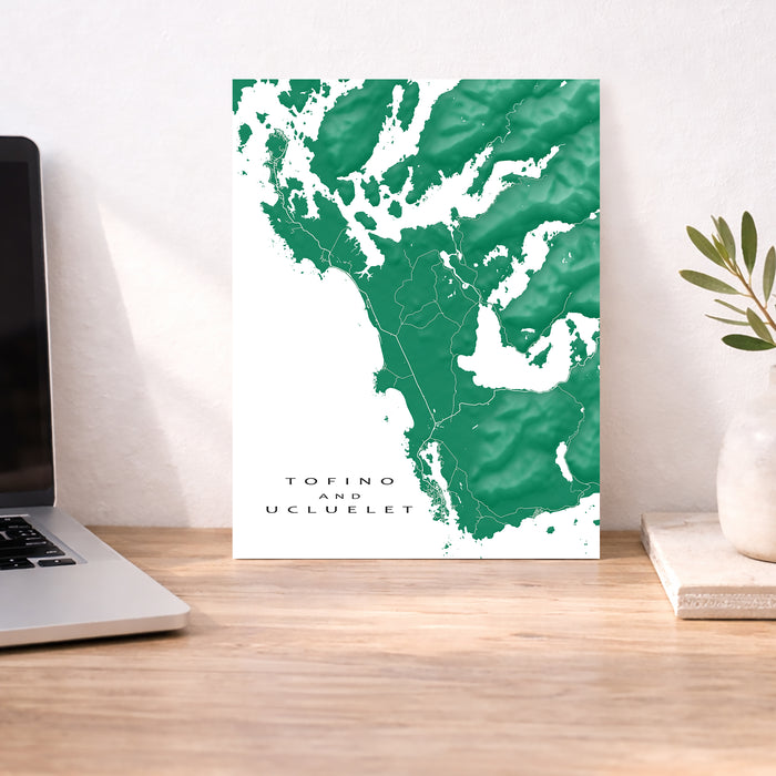 Map of Tofino and Ucluelet on a wall above a desk with a laptop and plant.