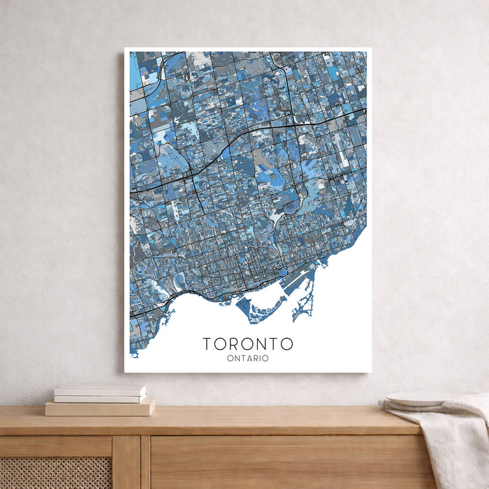 Framed map of Toronto, Ontario on a wall above a wooden shelf.