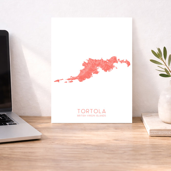 Map of Tortola on a white background next to a laptop on a wooden desk.