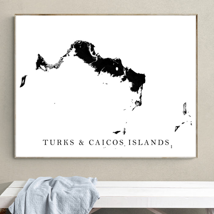 Framed map of Turks and Caicos Islands on a wall above a white bench.