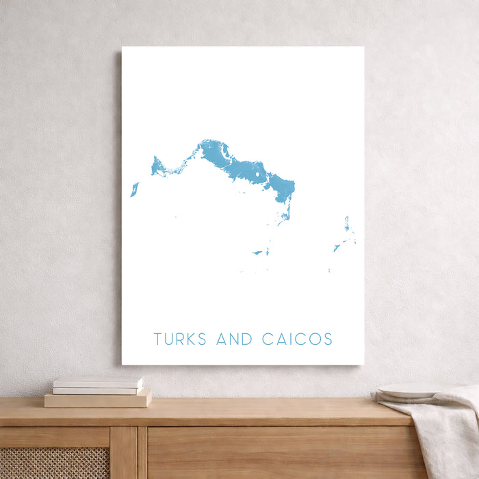 Map of Turks and Caicos on a white wall above a wooden shelf.
