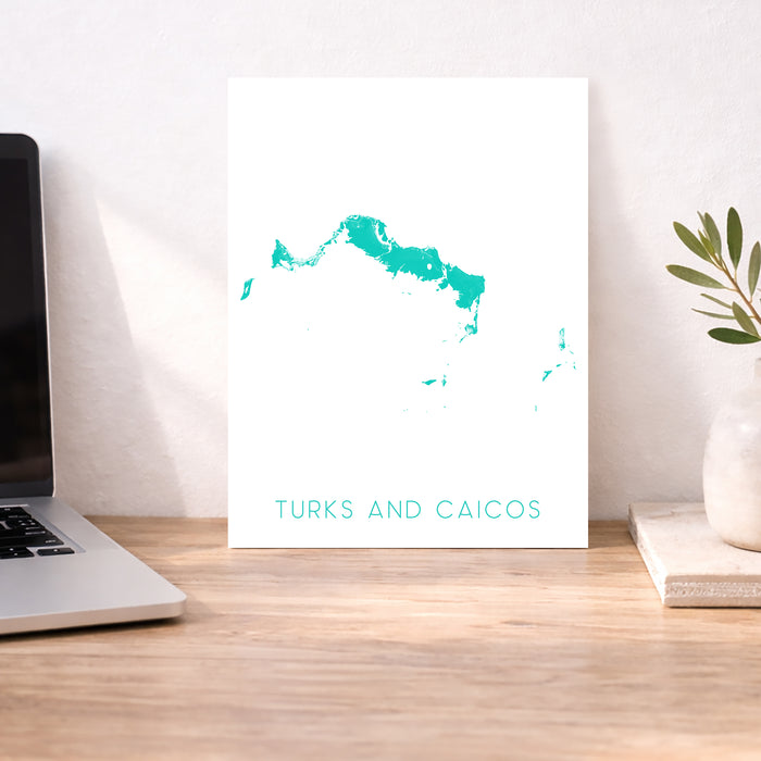 Map of Turks and Caicos on a desk with a laptop and plant