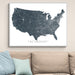 Framed map of the United States on a wall above a beige sofa with light blue pillows.