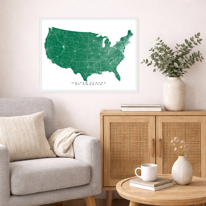 Living room with a framed map of the United States, a vase with plants, and a wooden cabinet.