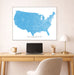 Framed map of the United States on a wall above a desk with a laptop and lamp.