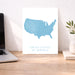 Map of the United States on a white background next to a laptop on a wooden desk.