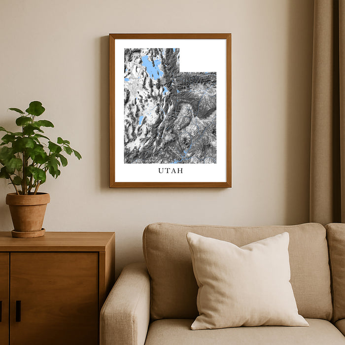 Framed map of Utah on a wall above a beige sofa with a plant beside it.