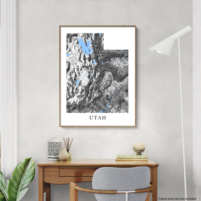 Framed map of Utah on a wall above a wooden desk with decor items.
