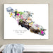A framed art print of Vancouver Island, Canada, featuring a hand-drawn design of driftwood, seashells, and flowers on a white background, hanging on a light gray wall above a white bench with a blue-gray throw blanket.