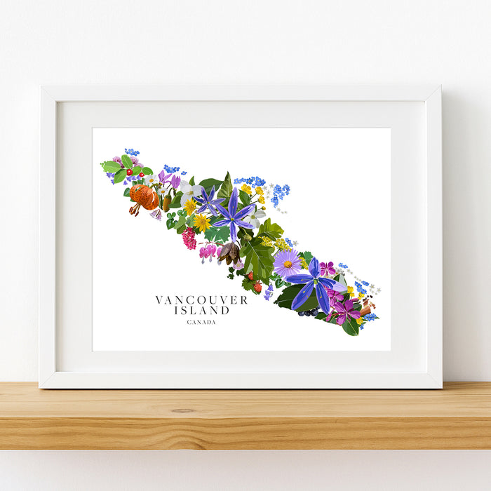 A framed watercolor art print of Vancouver Island filled with colorful wildflowers, displayed on a wooden shelf.