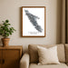 Framed map of Vancouver Island on a wall above a beige sofa with a plant beside it.