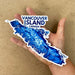 Hand holding a blue map sticker of Vancouver Island, Canada on a brown background