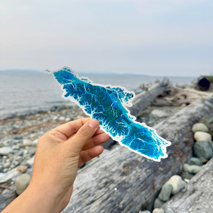 Hand holding a blue oceanic design sticker with a beach background