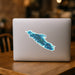 Laptop with a blue green Vancouver Island map sticker design on a wooden table