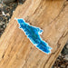 A blue and green Vancouver Island map sticker design on a brown wood background