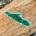 Green island-shaped sticker on a wooden surface