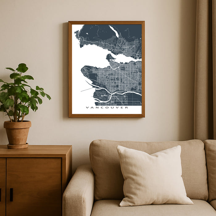Framed map of Vancouver on a wall above a beige sofa with a plant beside it.