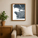 Framed map of Vancouver on a wall above a beige sofa with a plant beside it.