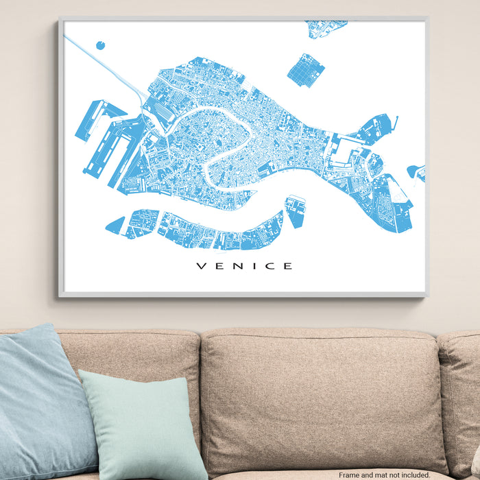 Framed map of Venice on a wall above a beige sofa with light blue pillows.