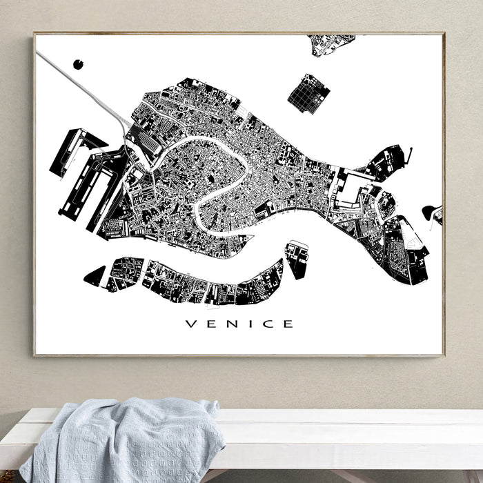 Framed black and white map of Venice on a wall above a white bench.