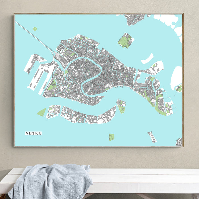Framed map of Venice on a light blue background, hanging on a wall.