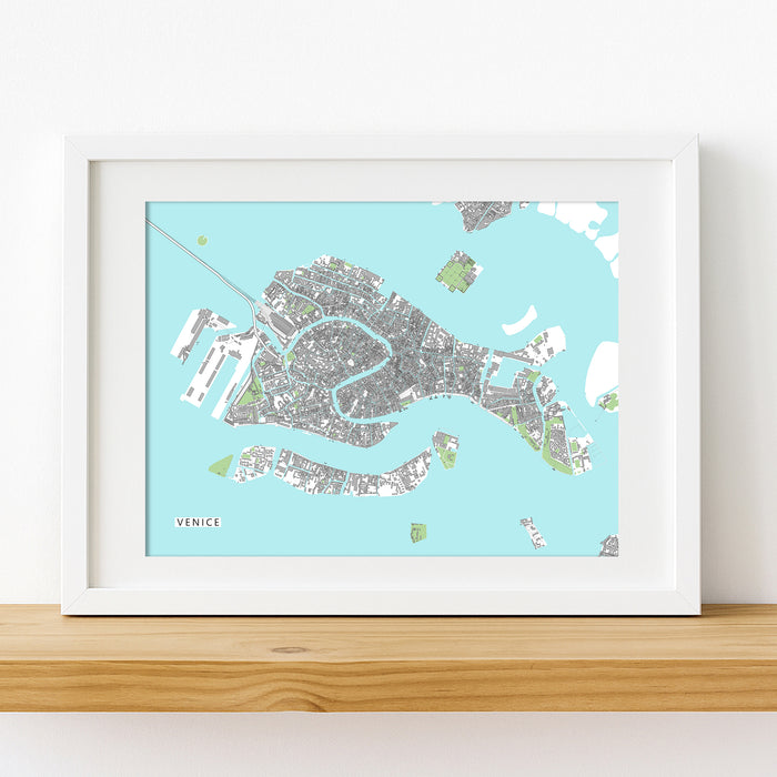 Framed map of Venice on a light blue background, displayed on a wooden surface.