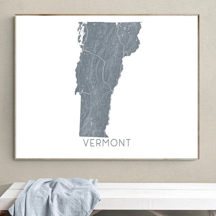 Framed map of Vermont on a wall above a white bench.