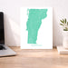 Map of Vermont on a desk with a laptop and plant
