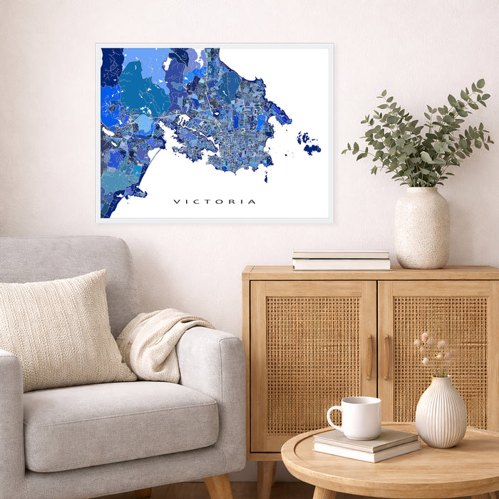Living room with a map of Victoria on the wall, a couch, and a side table with a plant and books.