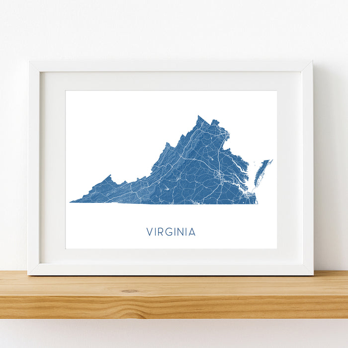 Framed map of Virginia on a white wall with wooden shelf