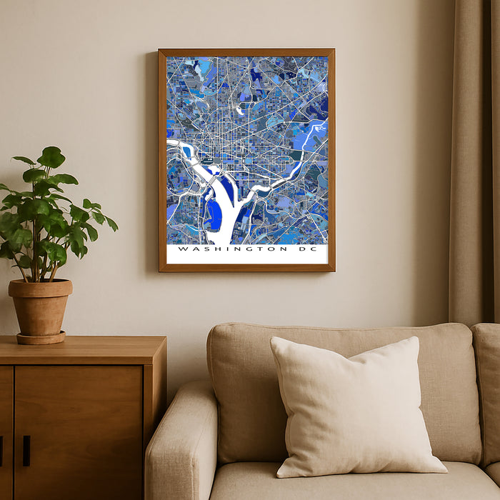 Framed map of Washington DC on a wall above a beige sofa with a plant beside it.