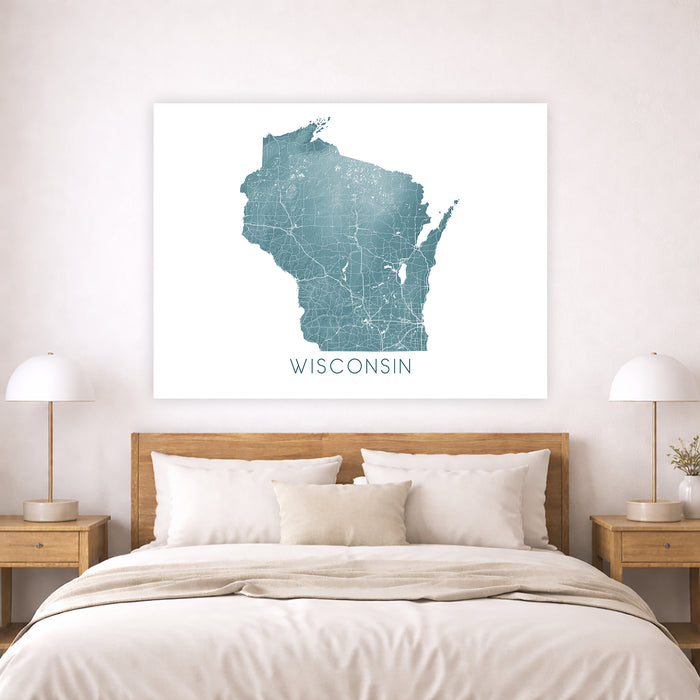 Framed map of Wisconsin on a wall above a bed in a bedroom.