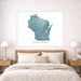 Framed map of Wisconsin on a wall above a bed in a bedroom.