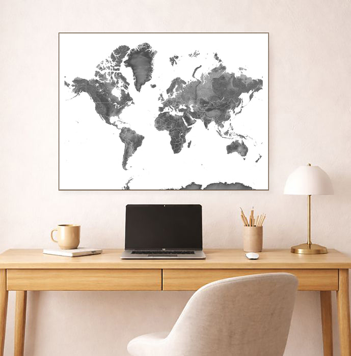 World map poster on a wall above a desk with a laptop and office items.