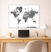 World map poster on a wall above a desk with a laptop and office items.